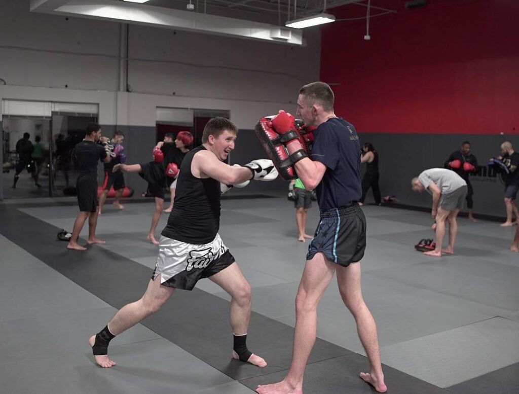 Martial arts student practicing punching on strike pads