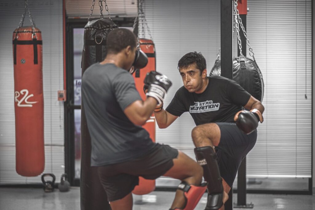 Two men preparing to kick each other with shin guards and punching gloves on
